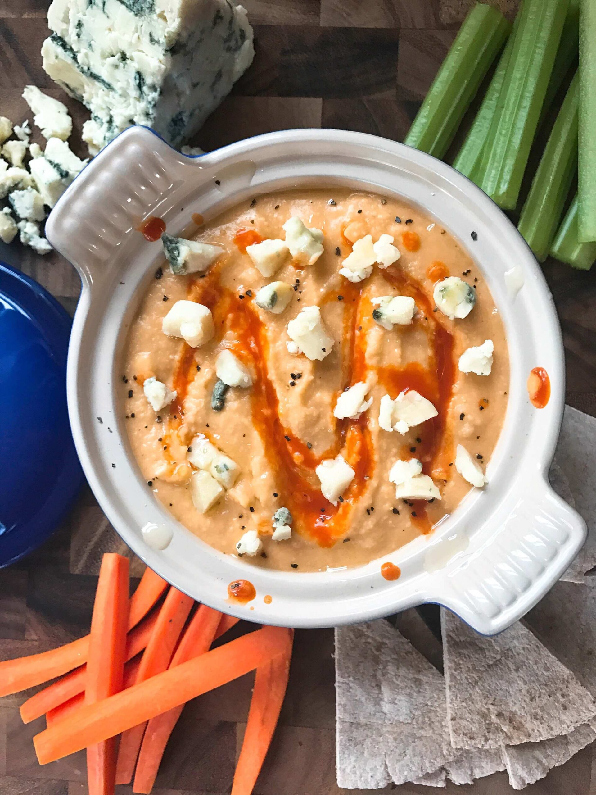 Top view of Buffalo Wing Hummus in a bowl with dippers around it