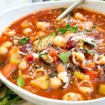 A bowl of Italian Minestrone Soup with a spoon in it.
