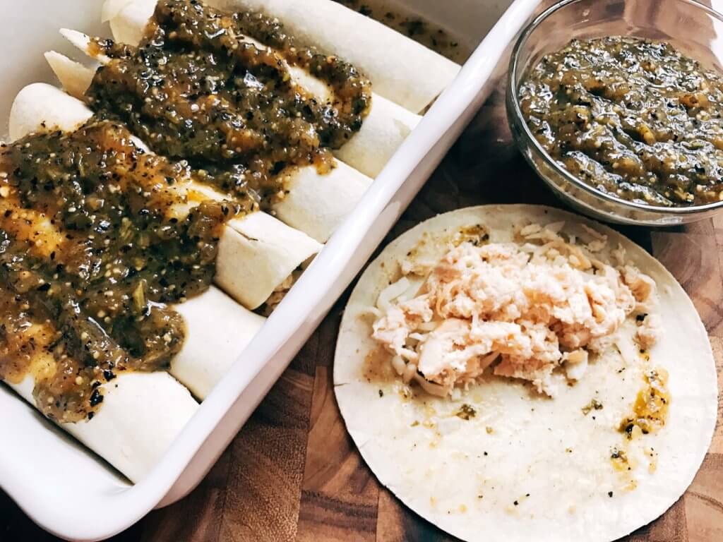 Enchiladas being filled, rolled, and sauced