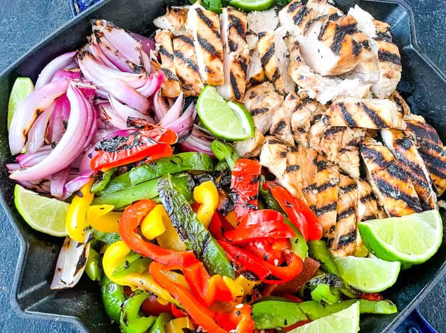 Chicken, peppers, and onions cut up in a skillet