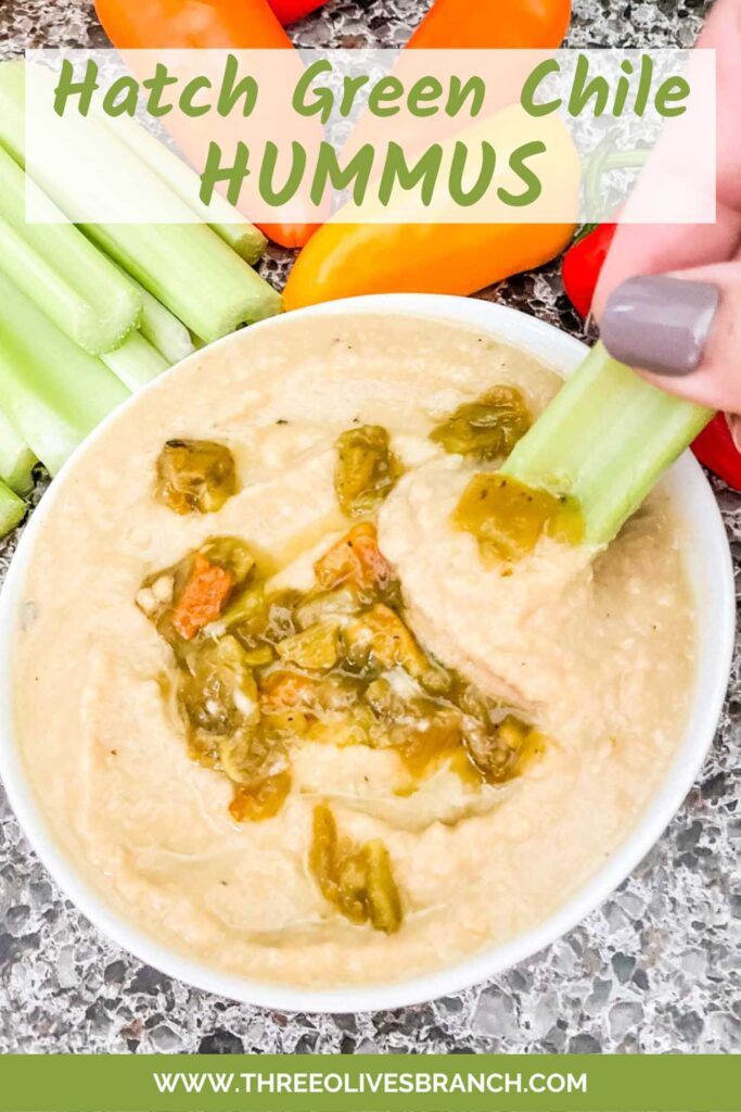 Pin of Roasted Hatch Green Chile Hummus in a small bowl with some peppers garnished on top. A hand dunking a piece of celery into the hummus. Title is listed at the top.