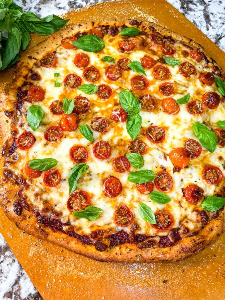 A full Caprese Pizza from the top on a pizza peel