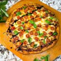 Caprese Pizza on a peel with drizzle balsamic vinegar