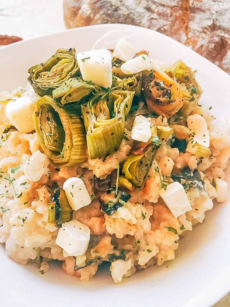 Close view of Roasted Leek and Brie Risotto in a bowl with leeks and cheese on top