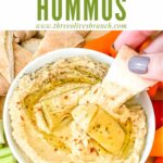 Pin of a hand dipping pita into Artichoke Lemon Hummus with title at top