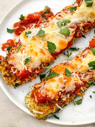 Two pieces of Three Cheese Zucchini Parmesan on a white plate