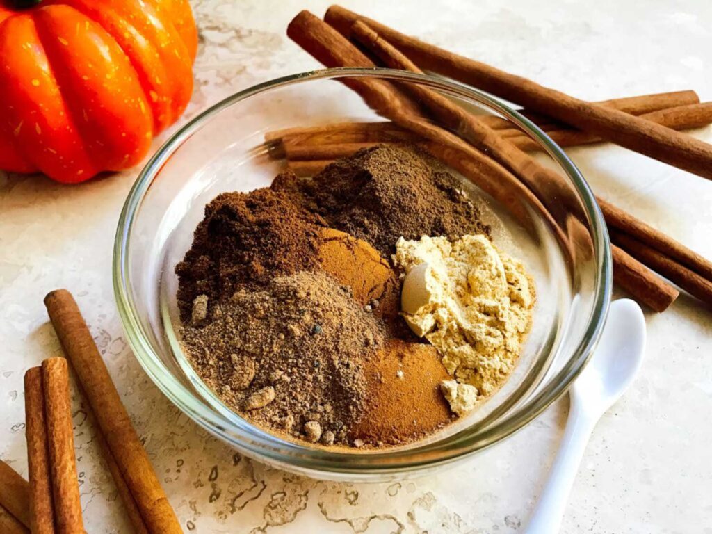 The spices for How to Make Pumpkin Pie Spice all in a glass bowl on a counter