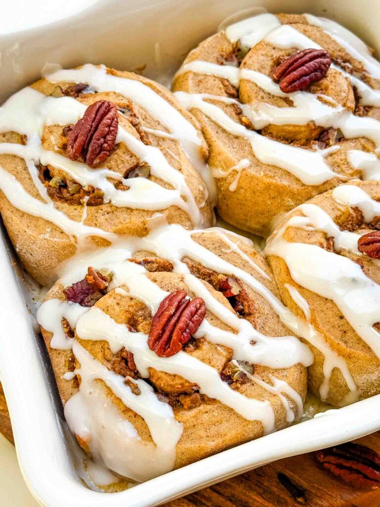 Pumpkin Spice Cinnamon Rolls with Maple Cream Cheese Glaze in a white baking dish.
