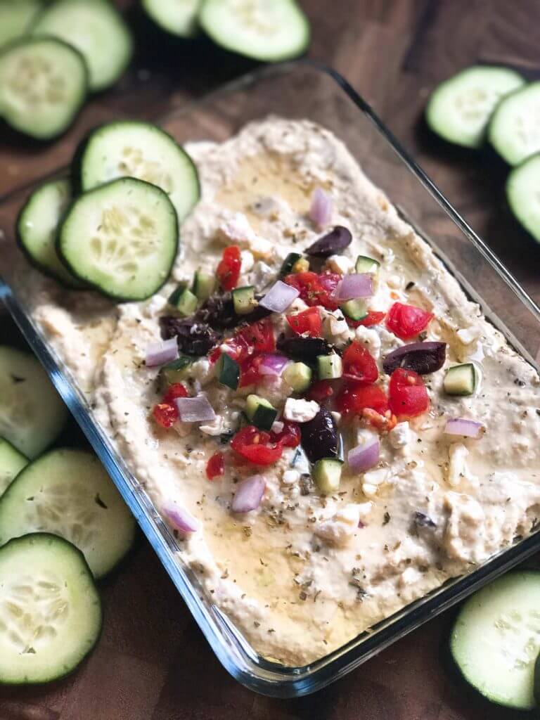 Less than 5 minutes to make this delicious and healthy hummus! Perfect as an appetizer, snack, or spread, the flavors of tzatziki and Greek salad are bright and fresh. Full of protein, vegetarian and vegan friendly. Perfect for game day! Greek Tzatziki Hummus | Three Olives Branch | www.threeolivesbranch.com