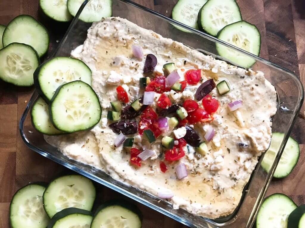 Less than 5 minutes to make this delicious and healthy hummus! Perfect as an appetizer, snack, or spread, the flavors of tzatziki and Greek salad are bright and fresh. Full of protein, vegetarian and vegan friendly. Perfect for game day! Greek Tzatziki Hummus | Three Olives Branch | www.threeolivesbranch.com