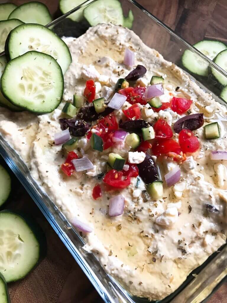 Less than 5 minutes to make this delicious and healthy hummus! Perfect as an appetizer, snack, or spread, the flavors of tzatziki and Greek salad are bright and fresh. Full of protein, vegetarian and vegan friendly. Perfect for game day! Greek Tzatziki Hummus | Three Olives Branch | www.threeolivesbranch.com