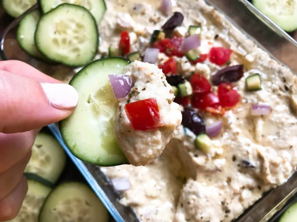 Less than 5 minutes to make this delicious and healthy hummus! Perfect as an appetizer, snack, or spread, the flavors of tzatziki and Greek salad are bright and fresh. Full of protein, vegetarian and vegan friendly. Perfect for game day! Greek Tzatziki Hummus | Three Olives Branch | www.threeolivesbranch.com
