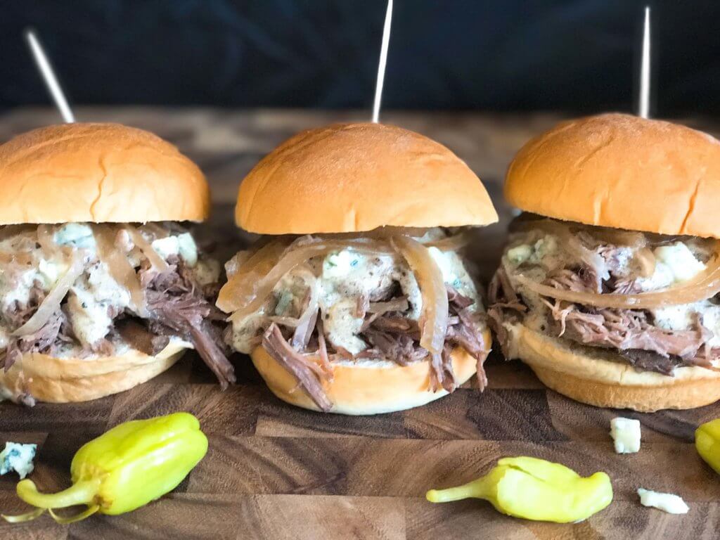 Use a slow cooker for simple and easy shredded steak sliders! Make the blue cheese sauce in advance for quick assembly. Perfect for your party, homegating, football or sport event like Super Bowl Sunday! Make them into a slider bar for customization. Kind friendly and lots of topping options like bacon, pickles, pepperoncini, and more! Bourbon Blue Cheese Steak Sliders | Three Olives Branch | www.threeolivesbranch.com