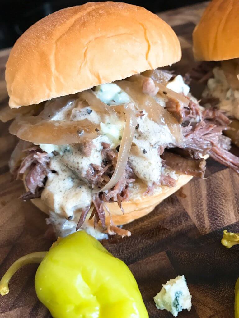 Use a slow cooker for simple and easy shredded steak sliders! Make the blue cheese sauce in advance for quick assembly. Perfect for your party, homegating, football or sport event like Super Bowl Sunday! Make them into a slider bar for customization. Kind friendly and lots of topping options like bacon, pickles, pepperoncini, and more! Bourbon Blue Cheese Steak Sliders | Three Olives Branch | www.threeolivesbranch.com