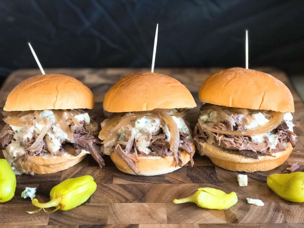 Use a slow cooker for simple and easy shredded steak sliders! Make the blue cheese sauce in advance for quick assembly. Perfect for your party, homegating, football or sport event like Super Bowl Sunday! Make them into a slider bar for customization. Kind friendly and lots of topping options like bacon, pickles, pepperoncini, and more! Bourbon Blue Cheese Steak Sliders | Three Olives Branch | www.threeolivesbranch.com