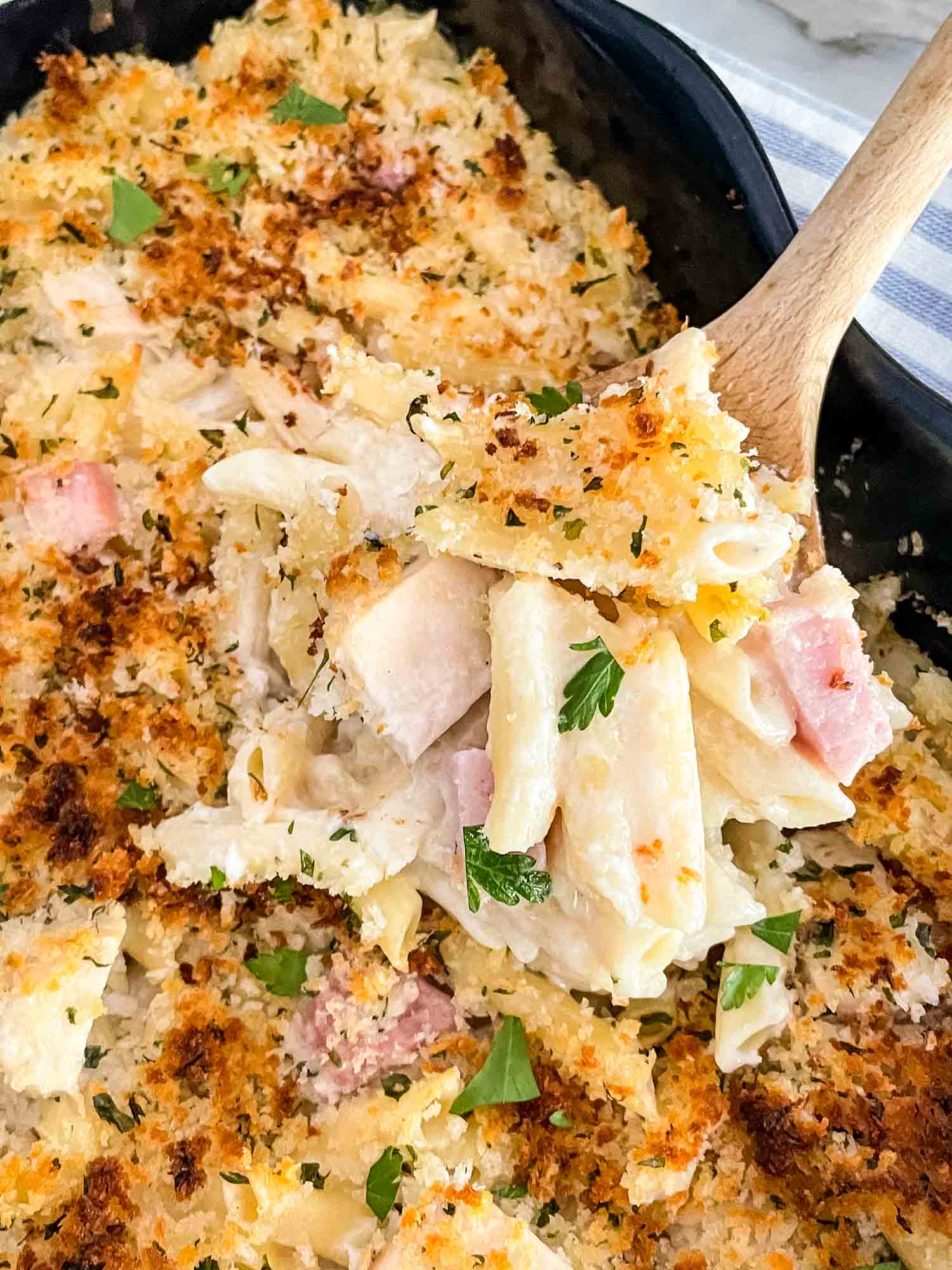 A spoon digging into a Chicken Cordon Bleu Casserole dish