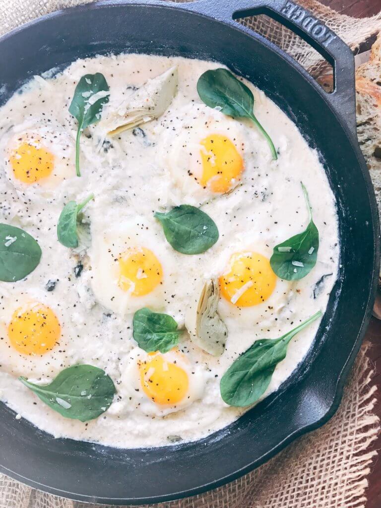 Less than 30 minutes for a simple, filling vegetarian dish that is perfect for breakfast, brunch, lunch or dinner. Also called Eggs in Purgatory, this twist on a classic dish is fast and easy and based on spinach artichoke dip. A creamy Parmesan cheese sauce is the base for the eggs, spinach, artichoke, and cheeses. Serve on top of bread for a filling meal! Spinach Artichoke Shakshuka | Three Olives Branch | www.threeolivesbranch.com