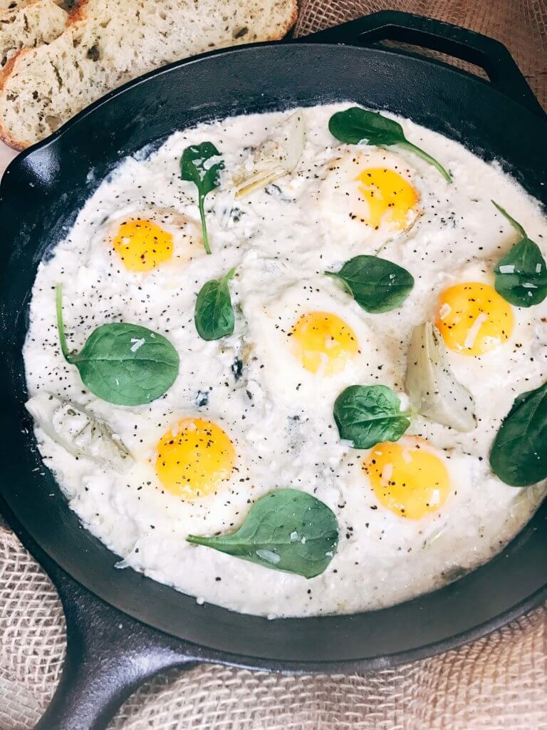 Less than 30 minutes for a simple, filling vegetarian dish that is perfect for breakfast, brunch, lunch or dinner. Also called Eggs in Purgatory, this twist on a classic dish is fast and easy and based on spinach artichoke dip. A creamy Parmesan cheese sauce is the base for the eggs, spinach, artichoke, and cheeses. Serve on top of bread for a filling meal! Spinach Artichoke Shakshuka | Three Olives Branch | www.threeolivesbranch.com