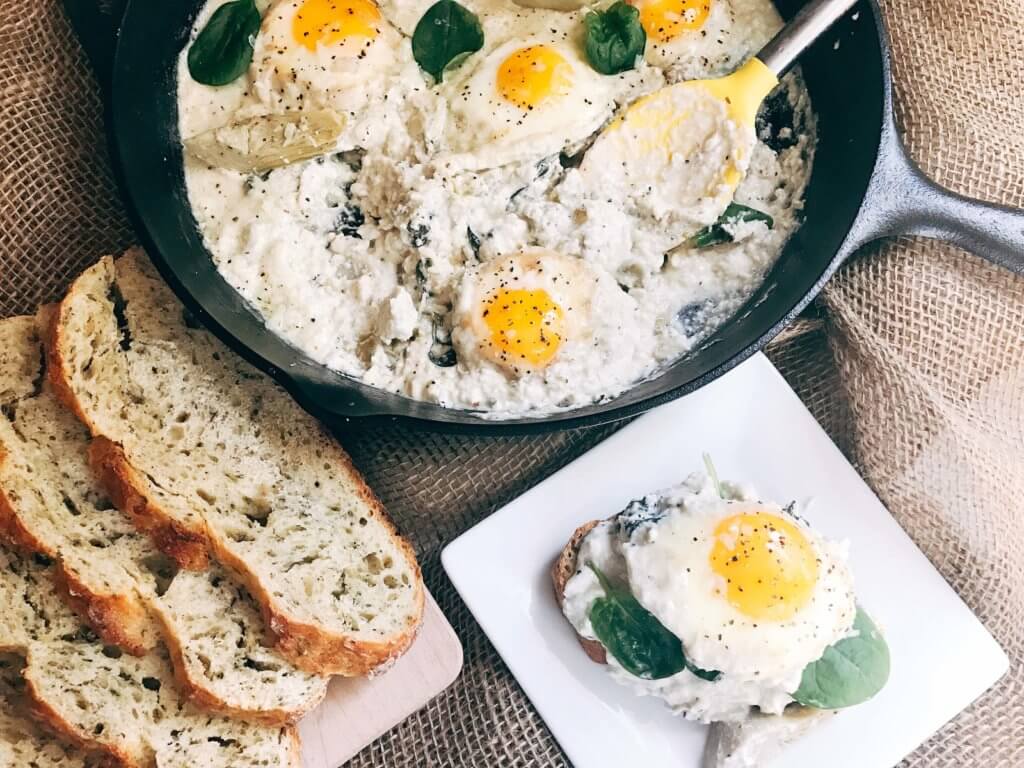 Less than 30 minutes for a simple, filling vegetarian dish that is perfect for breakfast, brunch, lunch or dinner. Also called Eggs in Purgatory, this twist on a classic dish is fast and easy and based on spinach artichoke dip. A creamy Parmesan cheese sauce is the base for the eggs, spinach, artichoke, and cheeses. Serve on top of bread for a filling meal! Spinach Artichoke Shakshuka | Three Olives Branch | www.threeolivesbranch.com