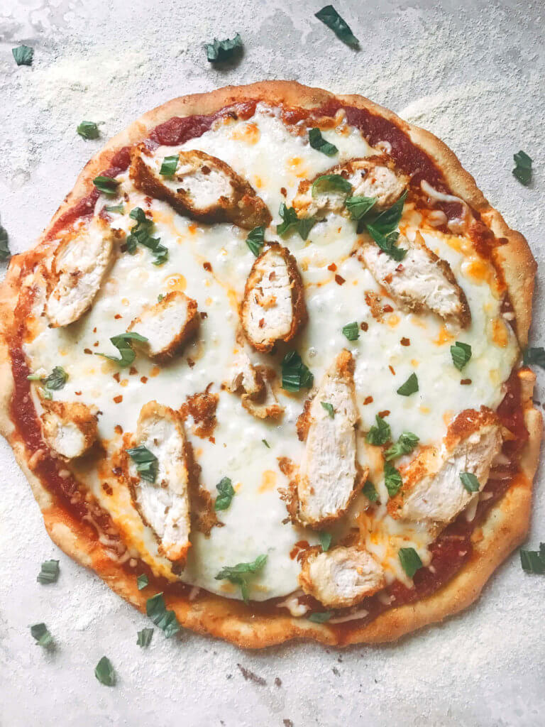 This pizza uses classic chicken parm flavors! Make the sauce, chicken, and crust in advance for a quick dinner. The pizza can be pre-made and frozen. Provolone, parmesan, basil, breaded chicken, and a red wine oregano sauce shine on this rosemary red pepper pizza dough. Great for pizza night or parties and entertaining. Chicken Parmesan Pizza | Three Olives Branch | www.threeolivesbranch.com