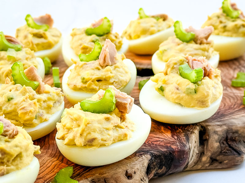 A close side view of Tuna Deviled Eggs on a wood board.