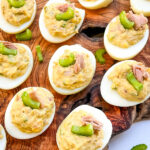 Looking down on Tuna Deviled Eggs spread out on a wood board.