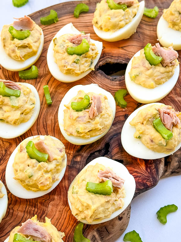 Looking down on Tuna Deviled Eggs spread out on a wood board.