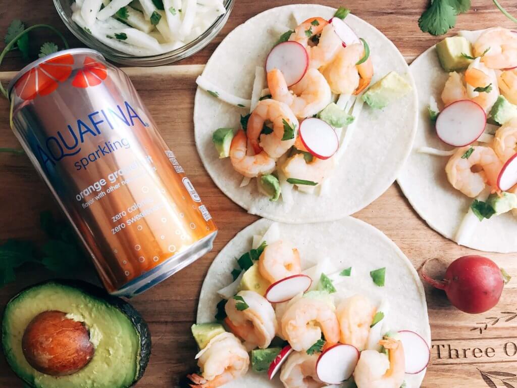 Less than 30 minutes for these simple and fresh shrimp tacos. Perfect for on-the-go food, full of bright and fresh flavors. Shrimp, orange, grapefruit, avocado, and jicama inspired by Aquafina Sparkling Water. A great twist on a seafood taco for Mexican night. Quick and easy to make, perfect for summer. Grapefruit Orange Shrimp Tacos with Jicama Slaw | Three Olives Branch | www.threeolivesbranch.com