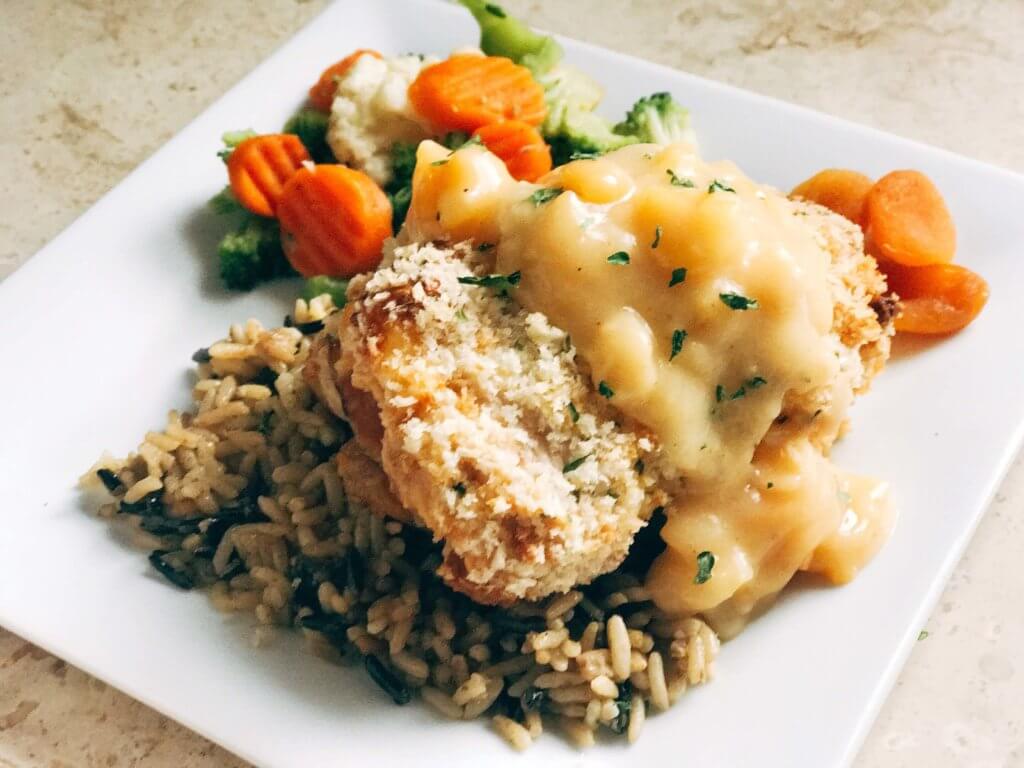 A slightly sweet twist on the classic! Dried apricots pair perfectly with the ham, monterey jack cheese, and seasonings in this recipe revamp. The creamy apricot white wine sauce is the perfect addition! A fun and memorable dinner that the entire family will love. Apricot Chicken Cordon Bleu | Three Olives Branch | www.threeolivesbranch.com
