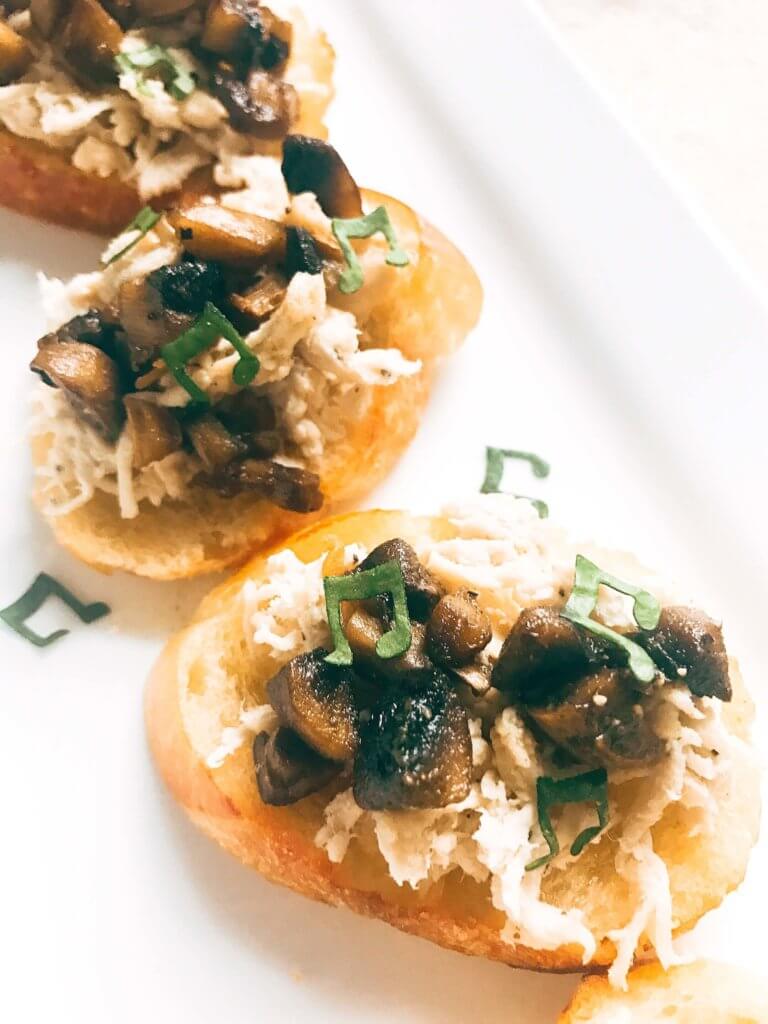 Ready in 20 minutes, this fast and easy appetizer is perfect for social gatherings like wine tastings! A great finger food that is simple to make, the baguette slices are toasted and topped with shredded chicken, mushrooms, butter, and sage. A great party appetizer and perfect to pair with wine. Buttered Chicken and Mushroom Crostini | Three Olives Branch | www.threeolivesbranch.com