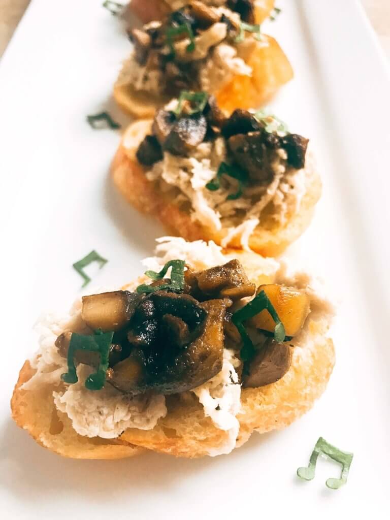 Ready in 20 minutes, this fast and easy appetizer is perfect for social gatherings like wine tastings! A great finger food that is simple to make, the baguette slices are toasted and topped with shredded chicken, mushrooms, butter, and sage. A great party appetizer and perfect to pair with wine. Buttered Chicken and Mushroom Crostini | Three Olives Branch | www.threeolivesbranch.com