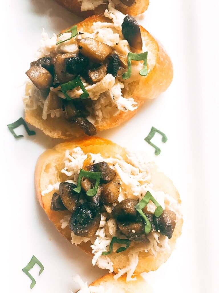 Ready in 20 minutes, this fast and easy appetizer is perfect for social gatherings like wine tastings! A great finger food that is simple to make, the baguette slices are toasted and topped with shredded chicken, mushrooms, butter, and sage. A great party appetizer and perfect to pair with wine. Buttered Chicken and Mushroom Crostini | Three Olives Branch | www.threeolivesbranch.com