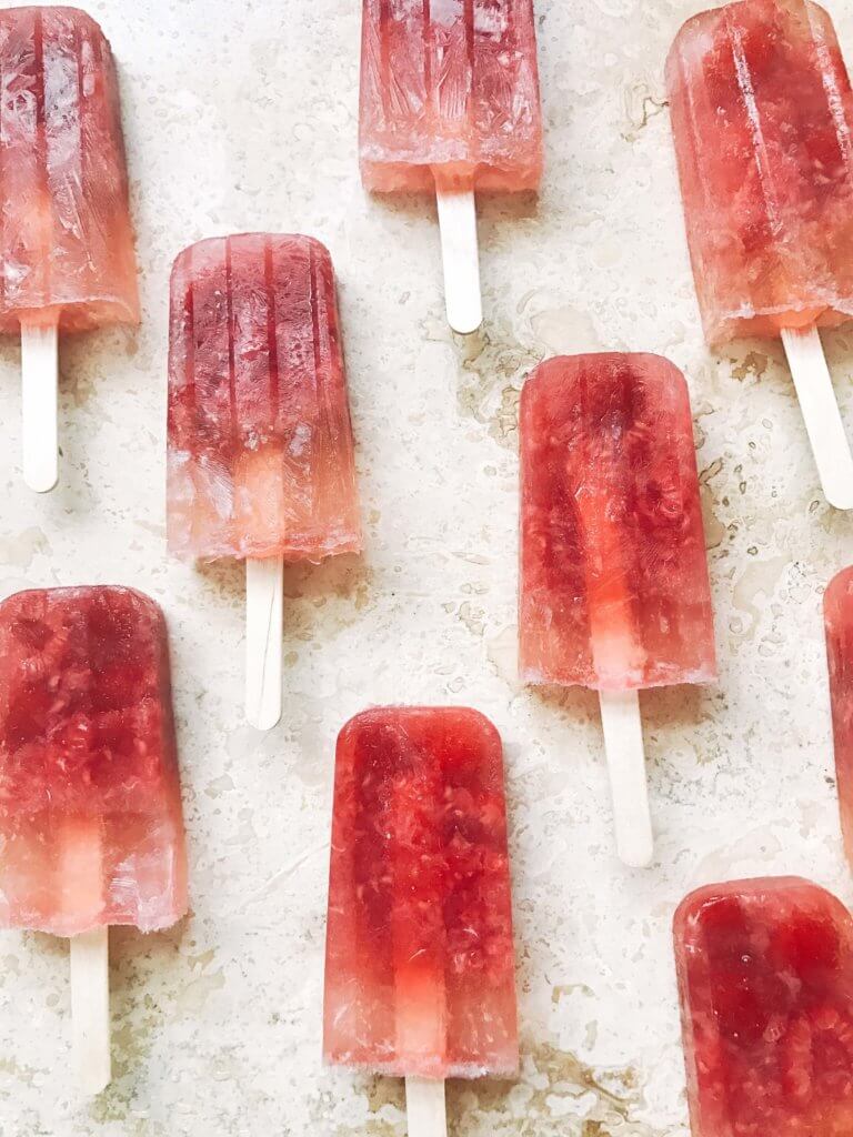 Popsicles made of rosé wine and raspberries! Simple to make and a great alcoholic adult treat for the warm and hot summer days. A twist on the frosé (frozé) trend, putting your favorite pink rose wine in popsicle form. A perfect treat or poptail for a cookout, barbecue, or grilling day. BBQ parties never tasted so good! Cocktail on a stick. Raspberry Rosé (Frosé) Popsicles | Three Olives Branch | www.threeolivesbranch.com