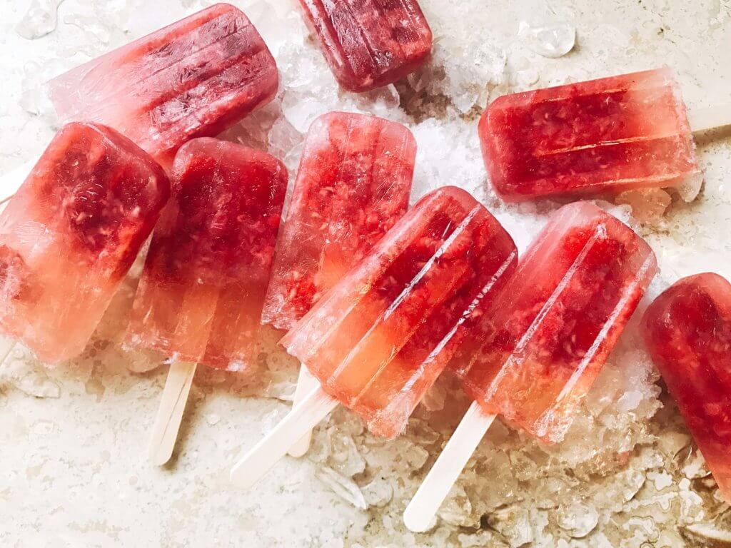 Popsicles made of rosé wine and raspberries! Simple to make and a great alcoholic adult treat for the warm and hot summer days. A twist on the frosé (frozé) trend, putting your favorite pink rose wine in popsicle form. A perfect treat or poptail for a cookout, barbecue, or grilling day. BBQ parties never tasted so good! Cocktail on a stick. Raspberry Rosé (Frosé) Popsicles | Three Olives Branch | www.threeolivesbranch.com