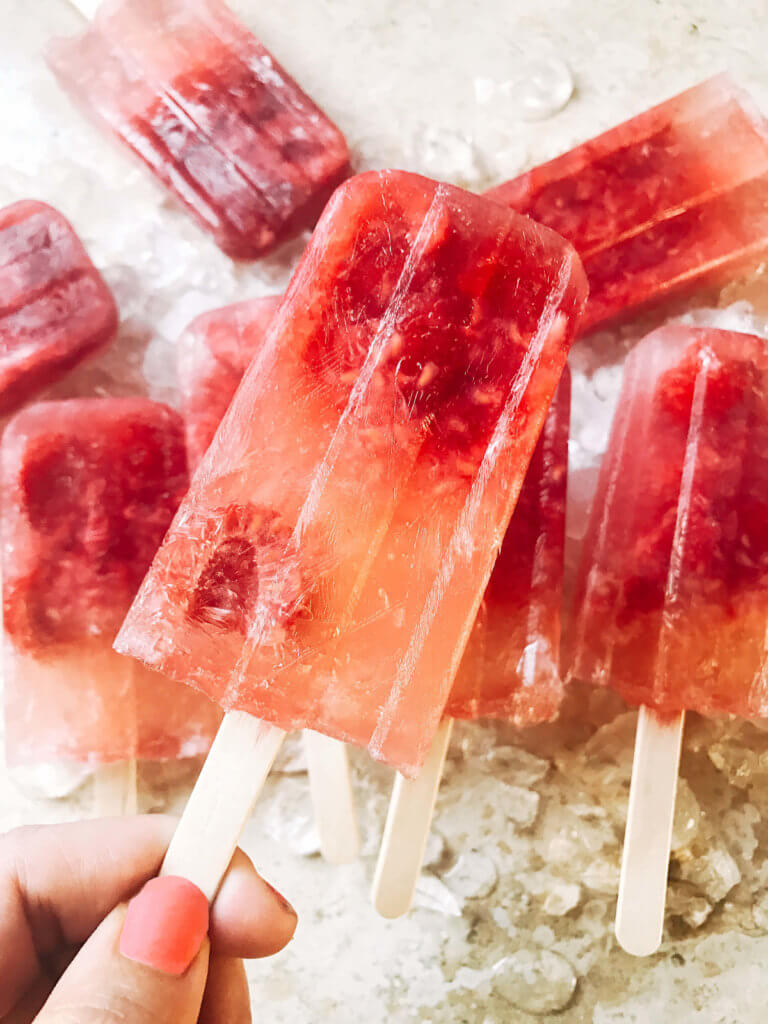 Popsicles made of rosé wine and raspberries! Simple to make and a great alcoholic adult treat for the warm and hot summer days. A twist on the frosé (frozé) trend, putting your favorite pink rose wine in popsicle form. A perfect treat or poptail for a cookout, barbecue, or grilling day. BBQ parties never tasted so good! Cocktail on a stick. Raspberry Rosé (Frosé) Popsicles | Three Olives Branch | www.threeolivesbranch.com