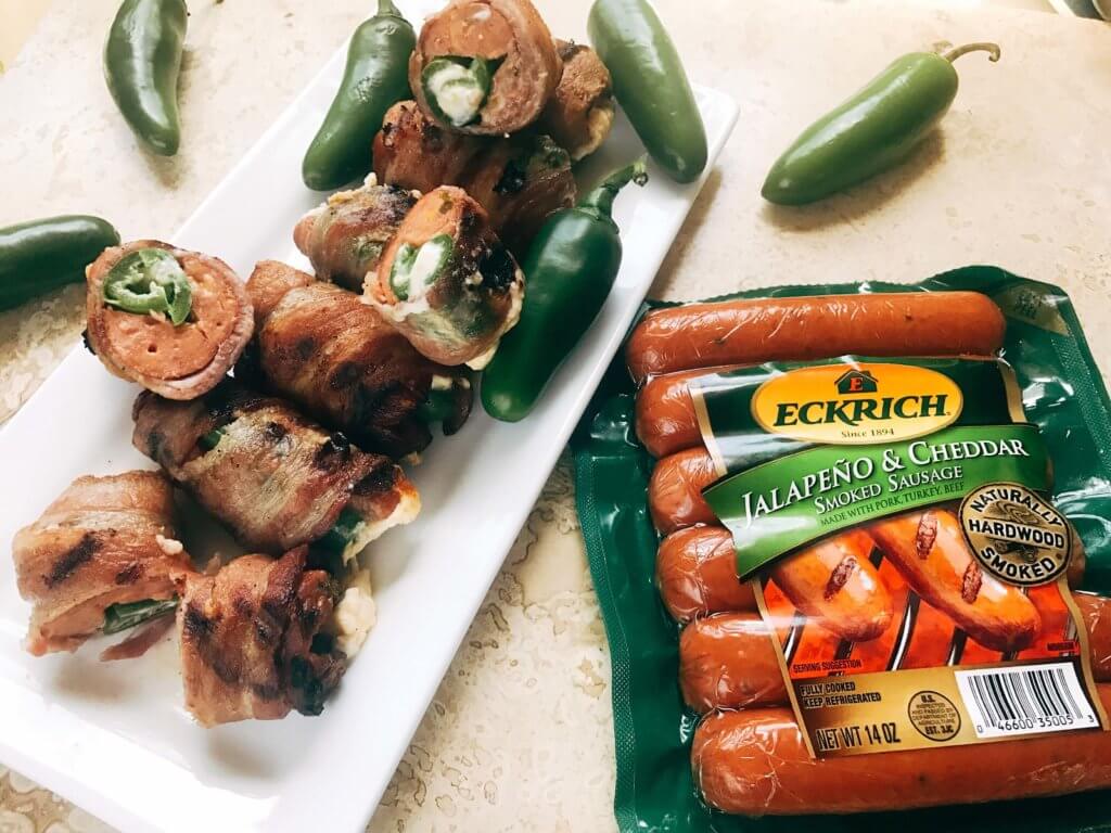 Grill up some of these smoky, cheesy treats for your next summer party. Eckrich Cheddar and Jalapeno Smoked Sausage is stuffed with a jalapeno pepper (which has been filled with cheddar and cream cheese), then rolled in bacon and grilled until crispy. They make such a fun appetizer or dinner for the pork lovers. A fun twist on a jalapeno popper and full of flavor. A great way to kick of football Sunday or game day. Cheddar Jalapeno Smoked Sausage Bacon Bombs | Three Olives Branch | www.threeolivesbranch.com