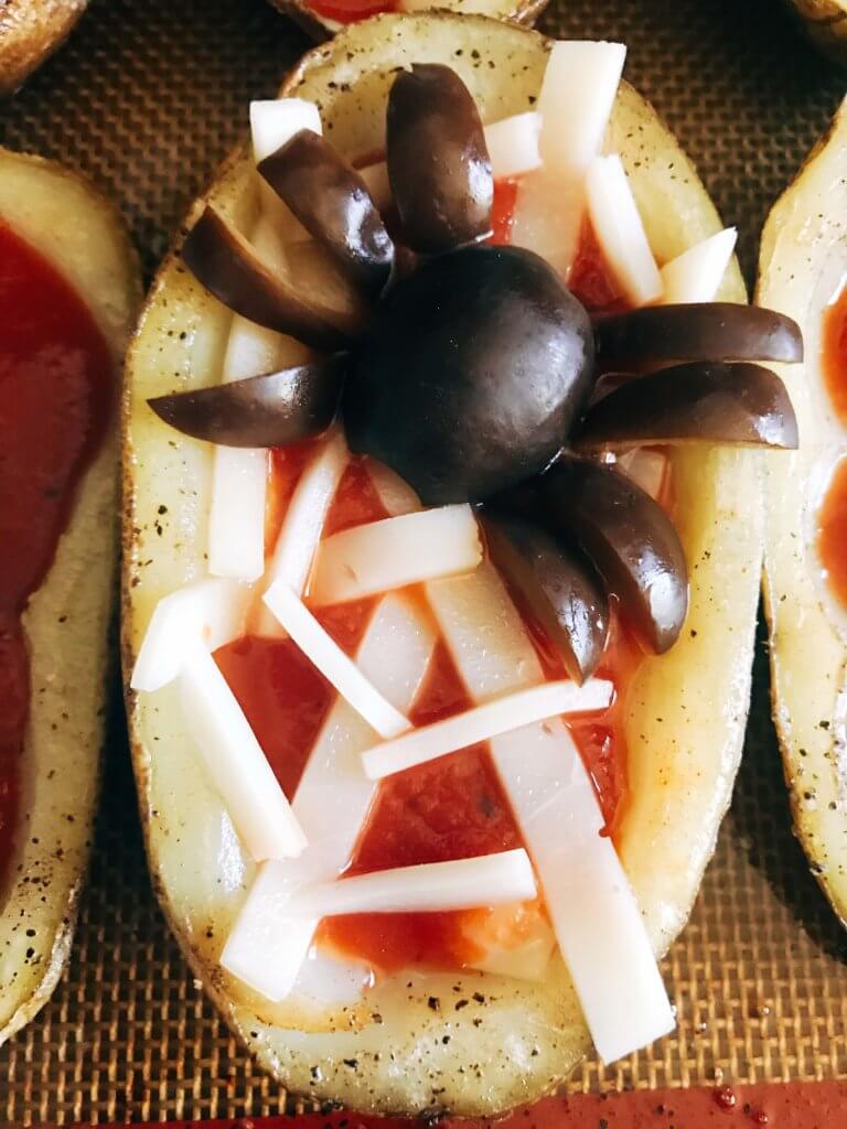 Fun, savory Halloween recipe perfect for fall parties and lunch or dinner. Potato skins are filled with pizza toppings of pizza sauce and provolone cheese, then decorated as a mummy, ghost, or spider web using additional cheese and black olives. A festive appetizer for adult and kid party food celebrating All Hallows' Eve. Vegetarian and gluten free. Halloween Pizza Potato Skins | Three Olives Branch | www.threeolivesbranch.com