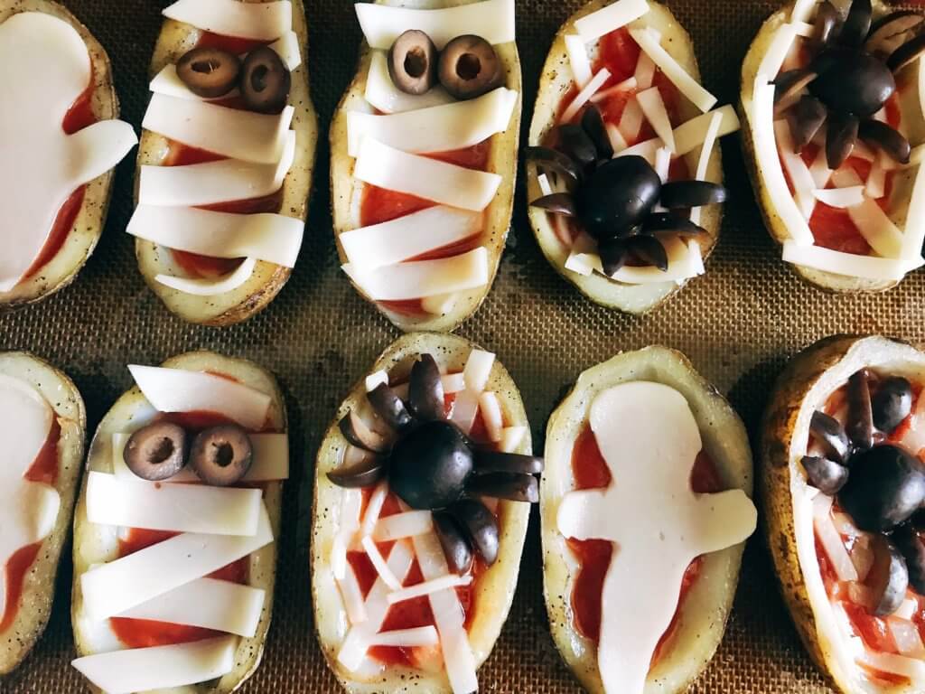 Fun, savory Halloween recipe perfect for fall parties and lunch or dinner. Potato skins are filled with pizza toppings of pizza sauce and provolone cheese, then decorated as a mummy, ghost, or spider web using additional cheese and black olives. A festive appetizer for adult and kid party food celebrating All Hallows' Eve. Vegetarian and gluten free. Halloween Pizza Potato Skins | Three Olives Branch | www.threeolivesbranch.com