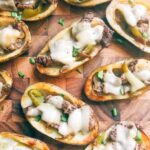 Philly Cheesesteak Potato Skins spread out on a wood cutting board