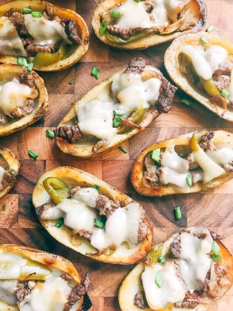 Philly Cheesesteak Potato Skins spread out on a wood cutting board