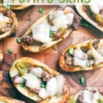 Pin of Philly Cheesesteak Potato Skins sitting on a wood cutting board with title at top
