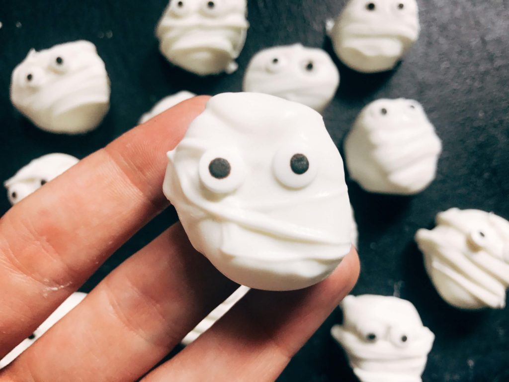 15 minutes to make these quick and simple mummy marshmallows! Large marshmallows are cut in half, covered in white candy melt with mummy wraps, and small candy eyes. Perfect for Halloween parties and a favorite among kids. Halloween Mummy Candy Dipped Marshmallows | Three Olives Branch | www.threeolivesbranch.com