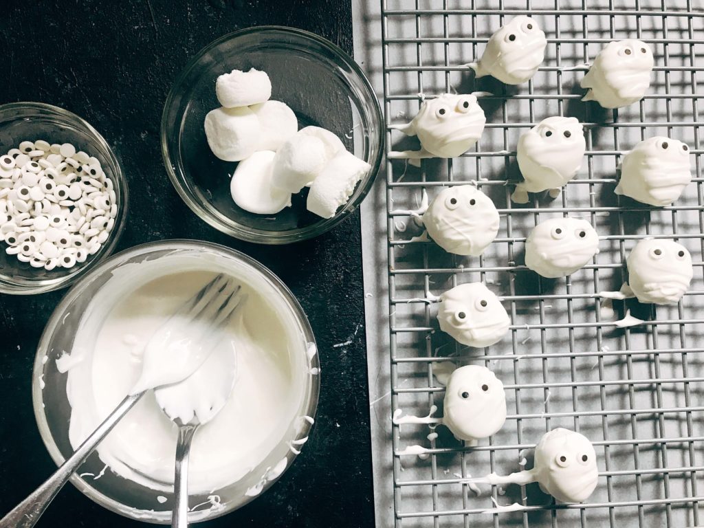 15 minutes to make these quick and simple mummy marshmallows! Large marshmallows are cut in half, covered in white candy melt with mummy wraps, and small candy eyes. Perfect for Halloween parties and a favorite among kids. Halloween Mummy Candy Dipped Marshmallows | Three Olives Branch | www.threeolivesbranch.com