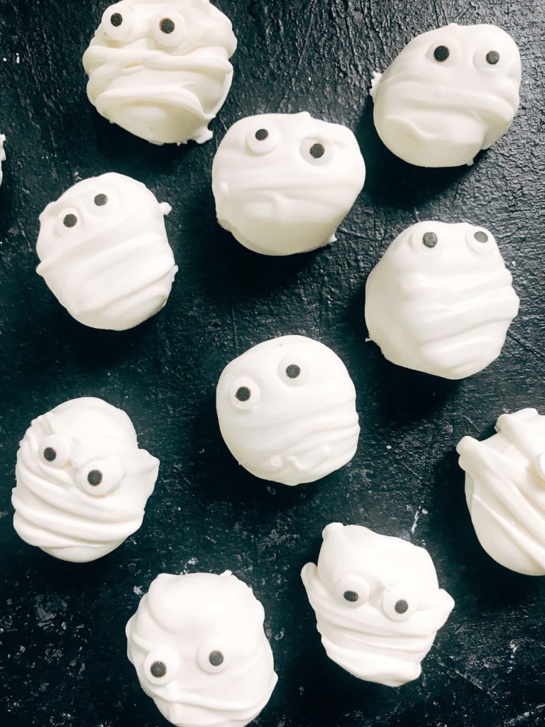 15 minutes to make these quick and simple mummy marshmallows! Large marshmallows are cut in half, covered in white candy melt with mummy wraps, and small candy eyes. Perfect for Halloween parties and a favorite among kids. Halloween Mummy Candy Dipped Marshmallows | Three Olives Branch | www.threeolivesbranch.com