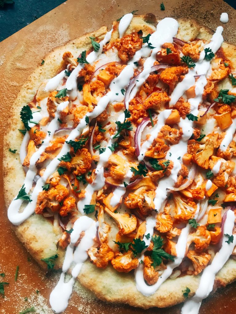 A vegetarian pizza recipe using the flavors of buffalo wings for inspiration. Roasted cauliflower is tossed with buffalo wing sauce on a ranch pizza crust. Great for game day and the Super Bowl to get a vegetarian buffalo recipe! Vegetarian Buffalo Cauliflower Pizza | Three Olives Branch | www.threeolivesbranch.com #superbowl #gameday #vegetarian #buffalowing