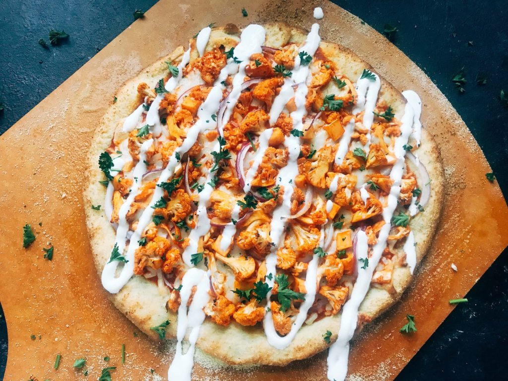 A vegetarian pizza recipe using the flavors of buffalo wings for inspiration. Roasted cauliflower is tossed with buffalo wing sauce on a ranch pizza crust. Great for game day and the Super Bowl to get a vegetarian buffalo recipe! Vegetarian Buffalo Cauliflower Pizza | Three Olives Branch | www.threeolivesbranch.com #superbowl #gameday #vegetarian #buffalowing