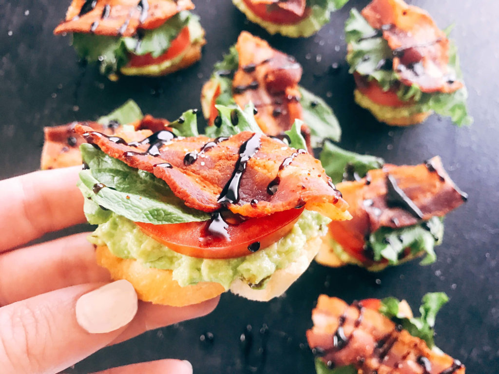 Quick and simple party appetizers. A twist on the BLT sandwich, these mini toasts are layered with avocado, tomato, lettuce, bacon, balsamic glaze, and some seasoned salt. Easy entertaining recipe. Avocado BLT Crostini | Three Olives Branch | www.threeolivesbranch.com #appetizer #blt #partyrecipe