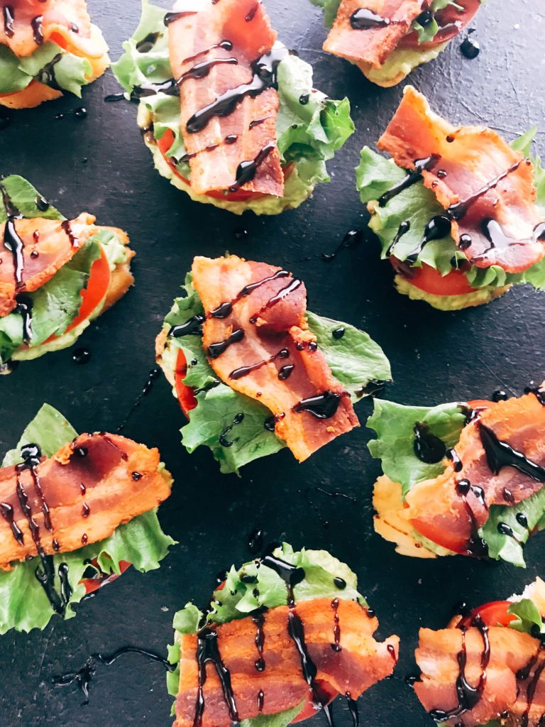 Quick and simple party appetizers. A twist on the BLT sandwich, these mini toasts are layered with avocado, tomato, lettuce, bacon, balsamic glaze, and some seasoned salt. Easy entertaining recipe. Avocado BLT Crostini | Three Olives Branch | www.threeolivesbranch.com #appetizer #blt #partyrecipe