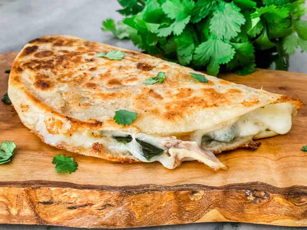 A full Chicken Poblano Quesadilla before being cut sitting on a wood board