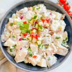 Top view of Greek Tzatziki Potato Salad in a gray bowl on a white conter with extra mix ins on top